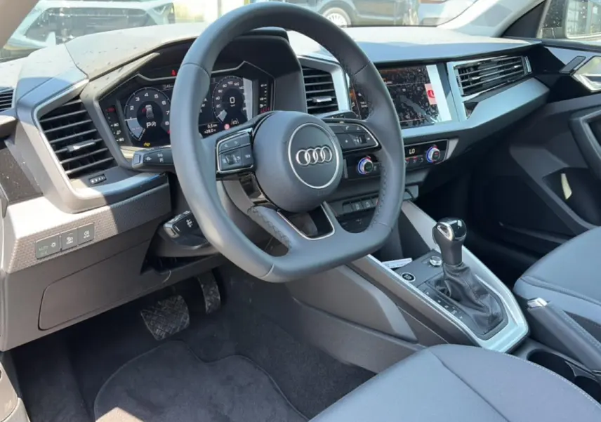 Vue intérieure côté conducteur de l'Audi A1 Sportback 30 TFSI 2026, volant cuir et tableau de bord numérique.
