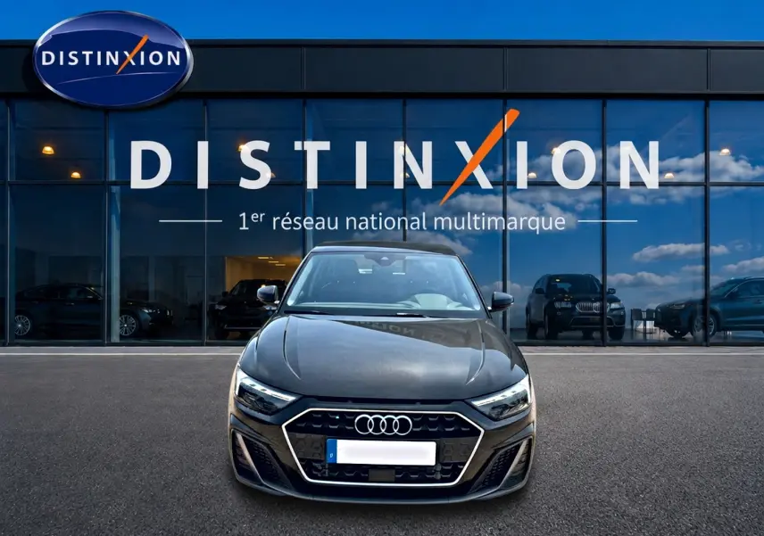Vue de face d'une Audi A1 Sportback noire 2026 avec calandre hexagonale et phares LED, devant un showroom Distinxion.