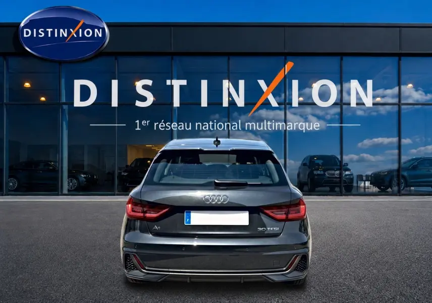 Vue arrière d'une Audi A1 Sportback noire 30 TFSI S line devant une vitrine Distinxion.
