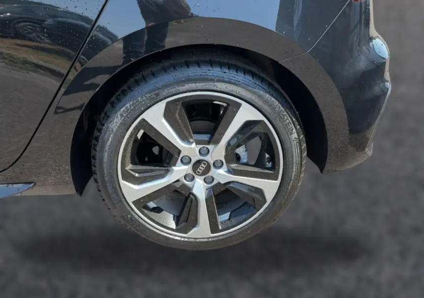Gros plan sur la roue arrière droite noire d’une Audi A1 Sportback 30 TFSI S line avec jante alu bicolore.