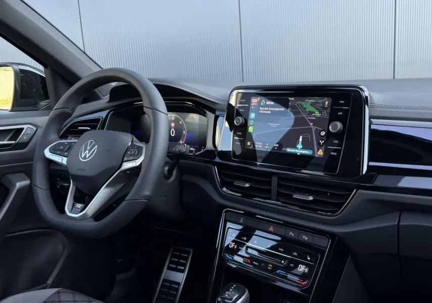 Intérieur du Volkswagen T-Roc 2025 R-Line, vue côté conducteur sur volant cuir, tableau de bord digital et écran tactile central.