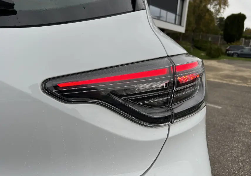 Gros plan sur le feu arrière droit rouge et noir de la Renault Clio V blanche 2025, finition Evolution.