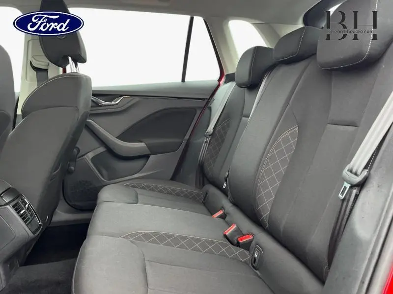 Vue intérieure arrière côté droit du Skoda Kamiq rouge Velvet, sièges tissu noir avec motifs quadrillés gris.