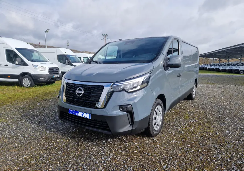 Nissan Primastar gris urbain vu en 3/4 avant droit sur un parking de véhicules utilitaires.