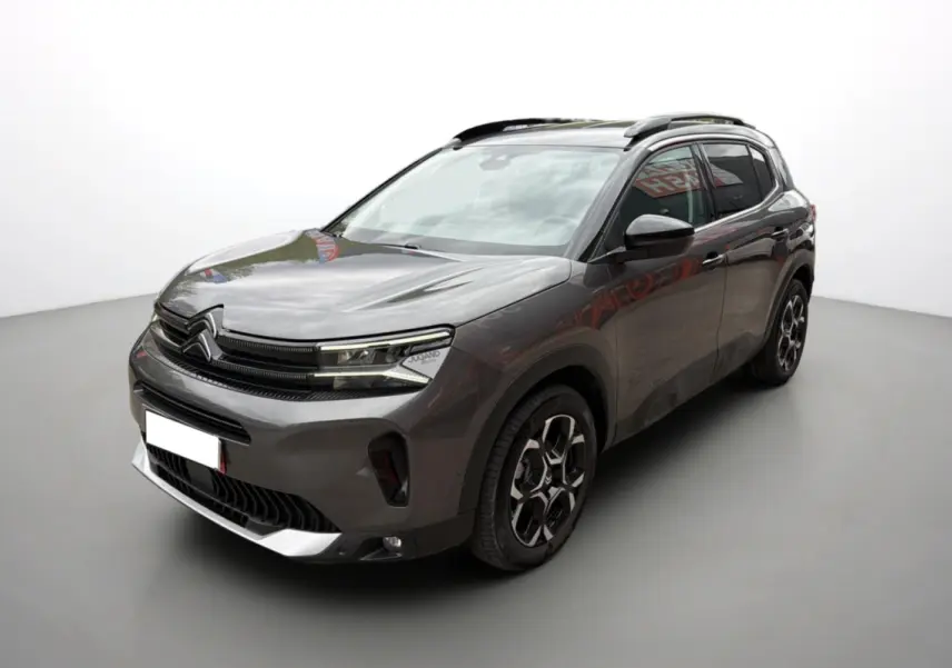 Citroën C5 Aircross gris platinium en 3/4 avant droit, avec barres de toit et jantes alu 18 pouces distinctives.