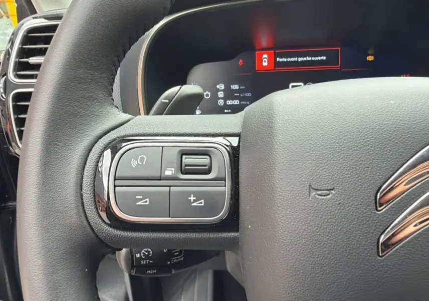 Gros plan sur le volant cuir multifonctions du Citroën C5 Aircross gris platinium, avec commandes intégrées et tableau de bord digital.