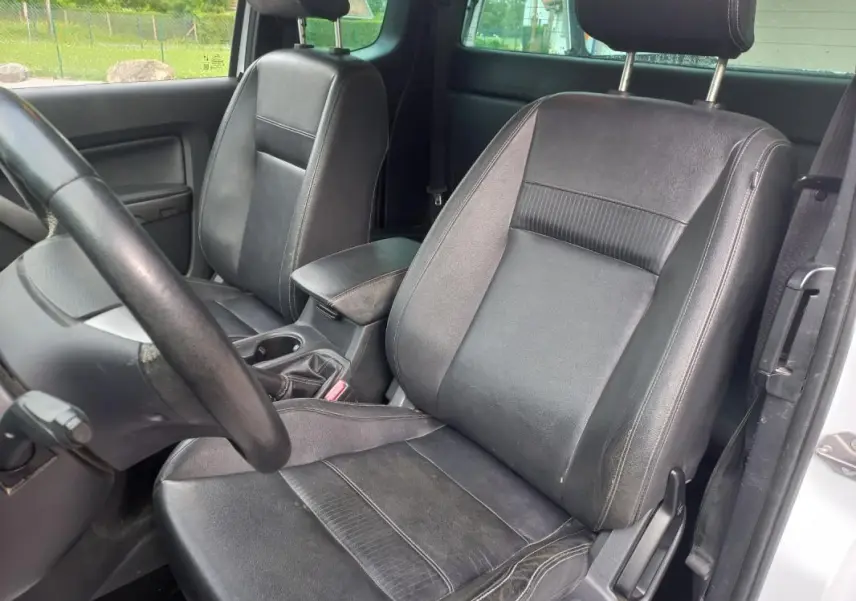 Vue intérieure côté conducteur du Ford Ranger blanc 2022, sièges en cuir noir et volant visible.