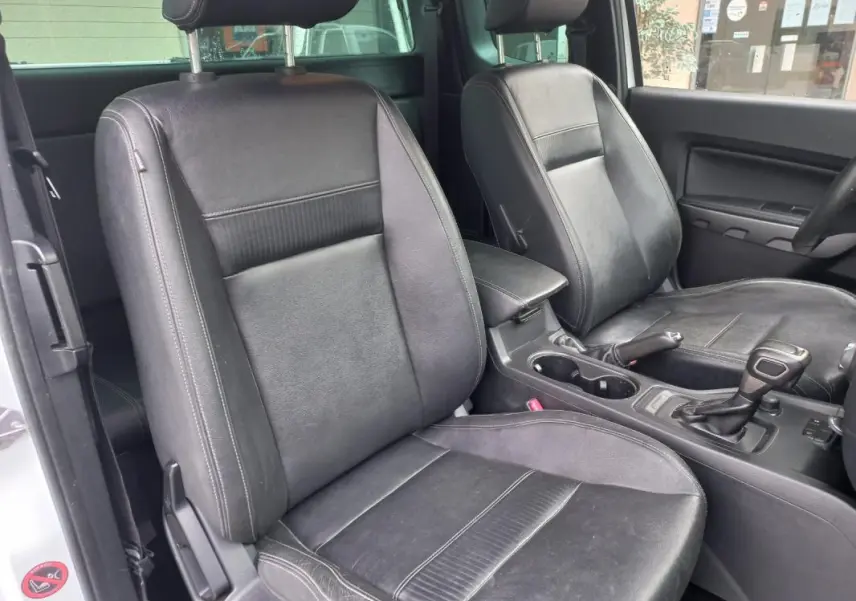 Vue intérieure du Ford Ranger 2022 en blanc, montrant les sièges avant en cuir noir et la console centrale avec levier de vitesse automatique.