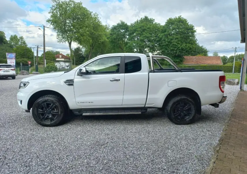 Ford Ranger Super Cabine Limited blanc vu de profil côté gauche, avec barres de protection chromées et jantes noires.