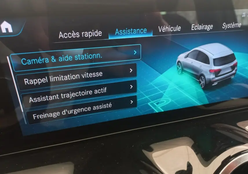 Écran tactile intérieur affichant le menu assistance avec une voiture grise vue en 3/4 arrière.