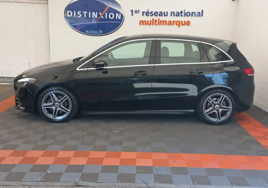 Vue de profil côté gauche d'une Mercedes Classe A berline A 200 AMG Line noire stationnée en intérieur.