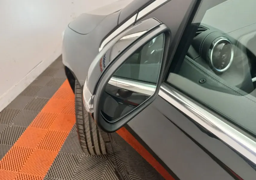 Gros plan sur le rétroviseur droit noir brillant d’une Mercedes Classe A Berline A 200 AMG Line 2021, intérieur cuir visible.