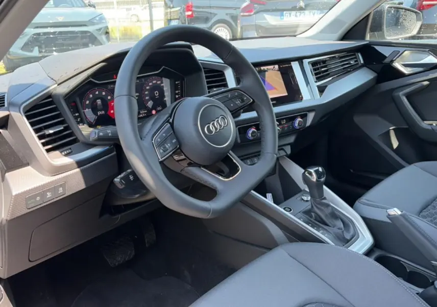 Vue intérieure côté conducteur de l'Audi A1 Sportback 2026, avec volant cuir multifonction et tableau de bord digital.