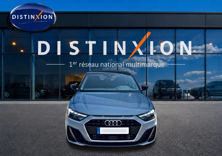 Vue avant d'une Audi A1 Sportback gris arrow avec calandre noire, stationnée devant une vitrine Distinxion.