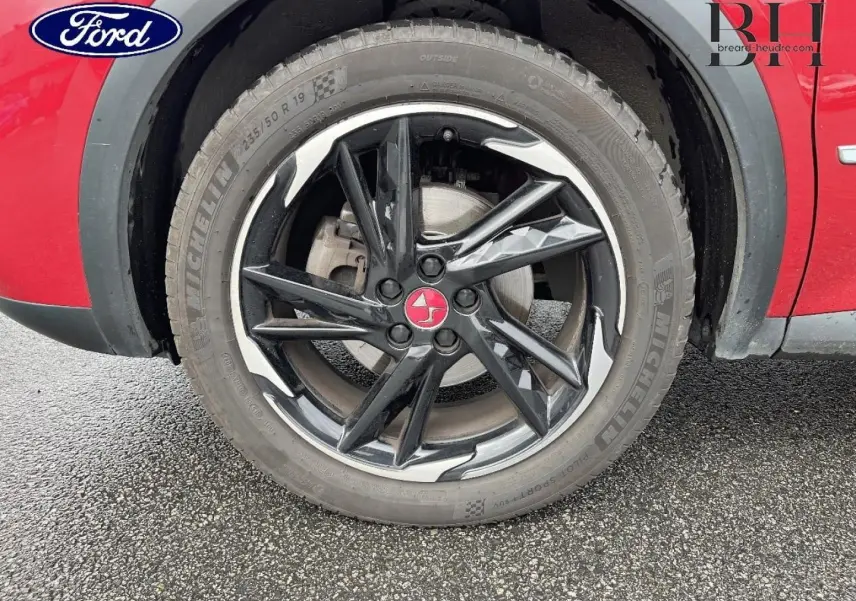 Gros plan sur la roue avant droite noire avec jante diamantée et carrosserie rouge absolu du DS7 Crossback.