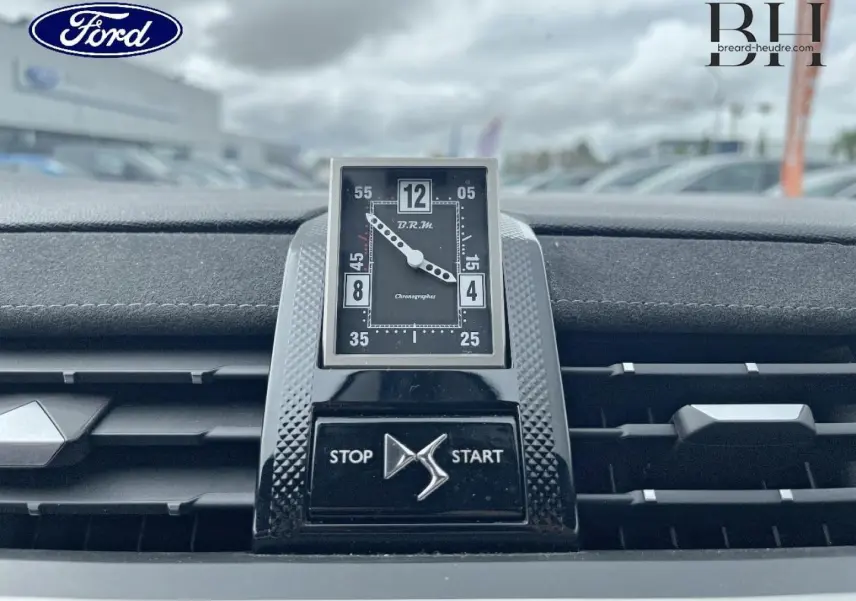 Gros plan sur l'horloge B.R.M R180 et la commande Stop/Start au centre du tableau de bord du DS7 Crossback rouge.