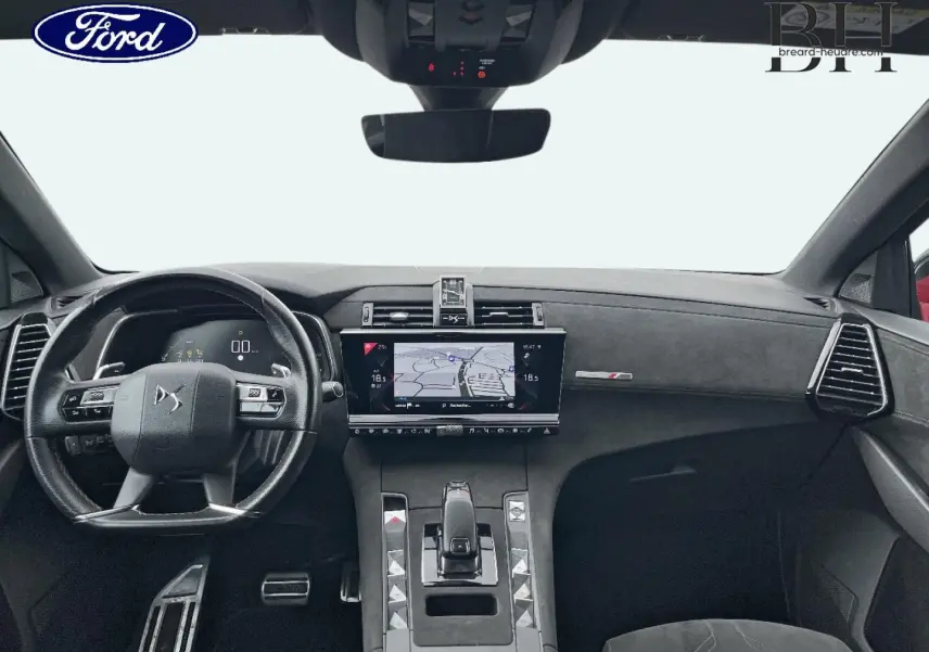 Vue intérieure avant du DS7 Crossback avec tableau de bord noir et écran tactile central affichant la navigation.