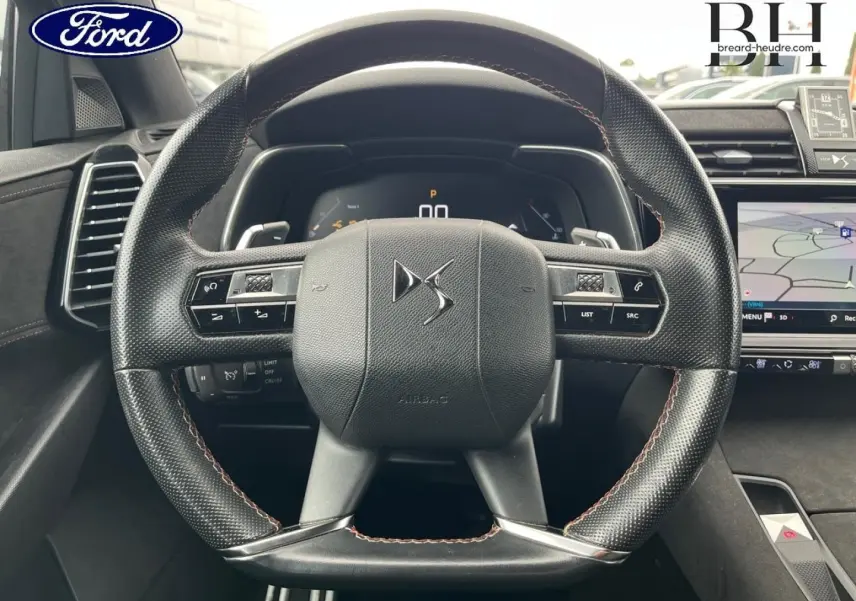 Volant DS en cuir noir avec coutures rouges et tableau de bord numérique d'un DS7 Crossback, vue de face intérieure.