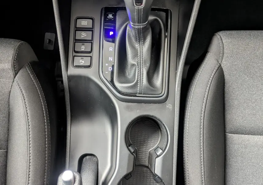 Vue plongeante sur la console centrale noire du Hyundai Tucson 2020, avec levier de vitesse automatique et porte-gobelets.