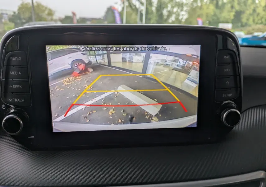 Vue intérieure sur l'écran de la caméra de recul du Hyundai Tucson blanc, affichant les lignes de guidage colorées.