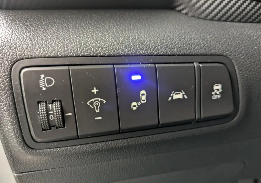 Gros plan sur les boutons de commande noirs du tableau de bord intérieur du Hyundai Tucson 2020, avec témoin bleu allumé.