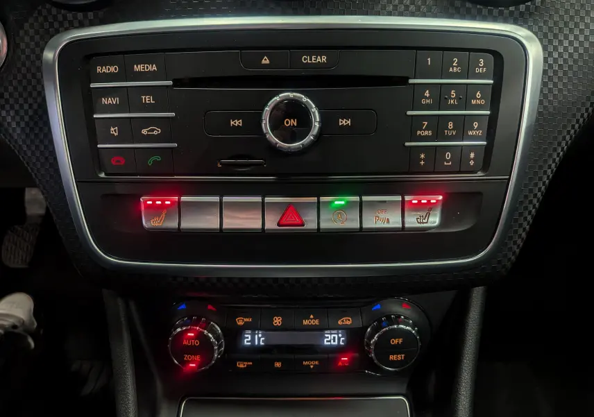 Console centrale de Mercedes Classe A 200d 2016 avec commandes radio, climatisation bi-zone et sièges chauffants activés.