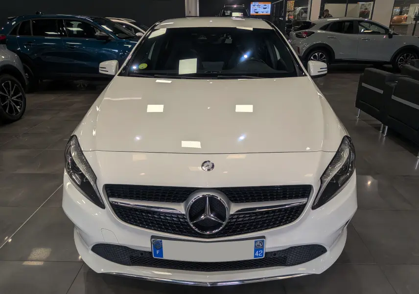 Vue frontale d'une Mercedes Classe A 200d blanche 2016 exposée en showroom avec calandre noire et logo chromé.