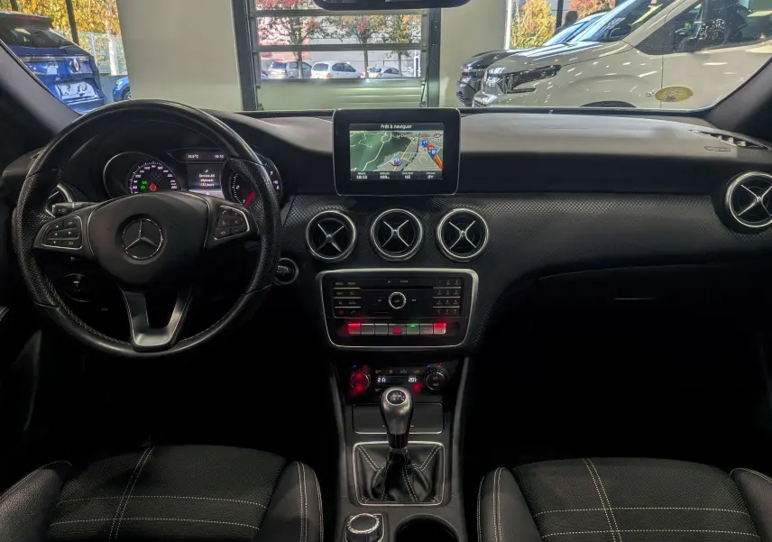 Vue intérieure du tableau de bord noir de la Mercedes Classe A 200d 2016 avec écran central et boîte manuelle.