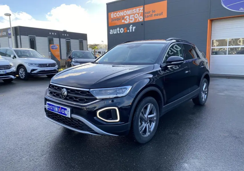 Volkswagen T-Roc noir nacré 2025 en 3/4 avant droit, avec feux LED et jantes alliage visibles sur parking.
