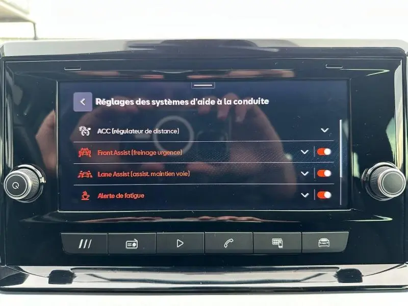 Écran tactile central du SEAT Arona 2025 affichant les réglages des aides à la conduite, avec boutons de commande en dessous.