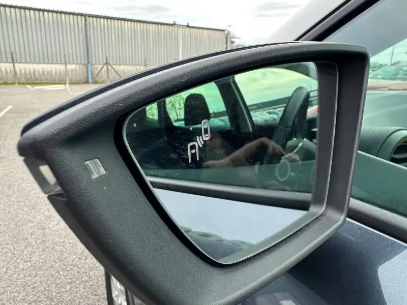 Rétroviseur côté droit du SEAT Arona gris magnétique avec toit blanc, reflétant l’intérieur et une personne au volant.