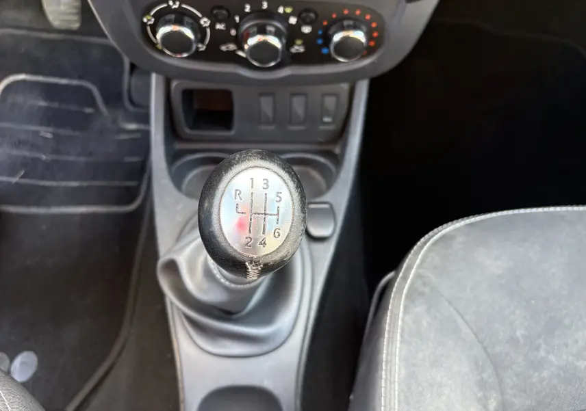 Gros plan sur le levier de vitesses manuel noir du Dacia Duster 2014, avec console centrale et sièges gris visibles.