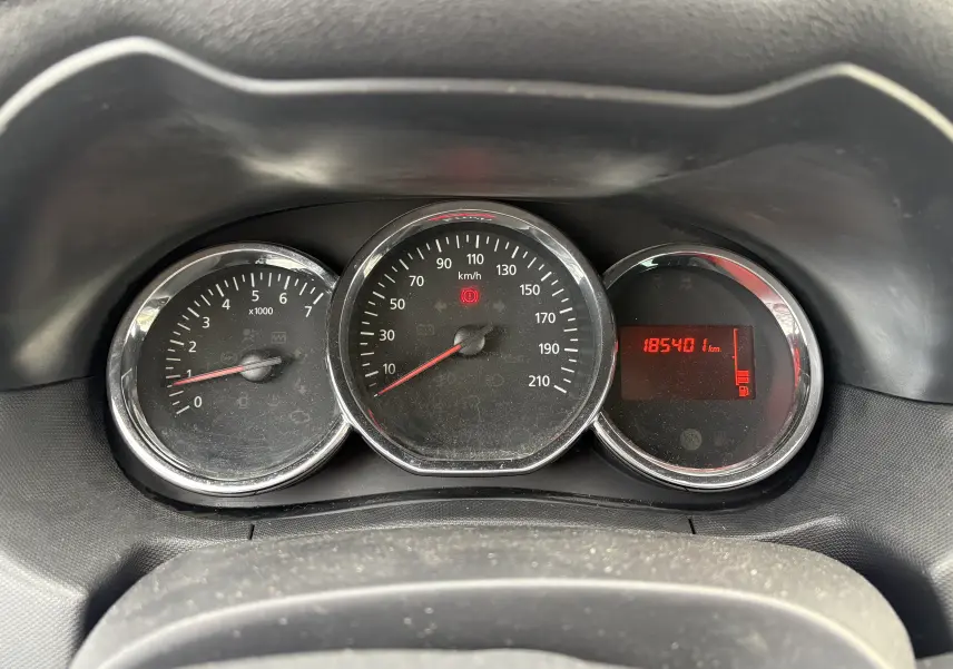 Gros plan sur le tableau de bord du Dacia Duster 2014, avec compte-tours, compteur de vitesse et affichage digital rouge.