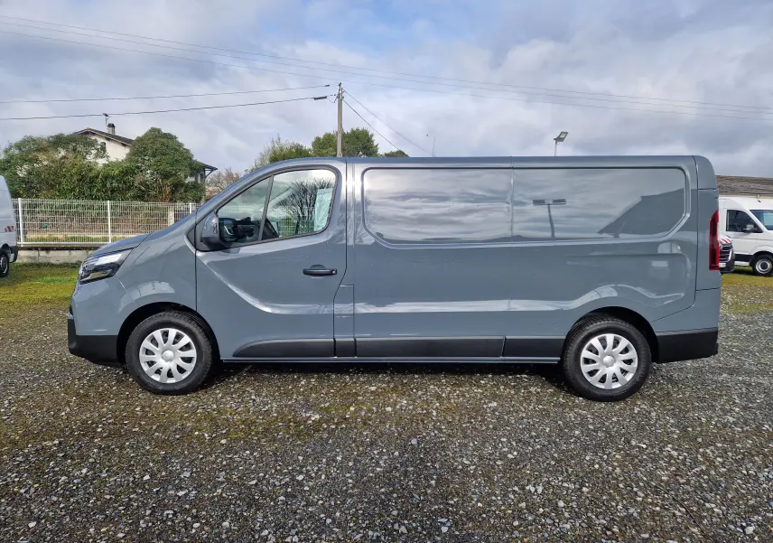 Vue de profil côté gauche d’un utilitaire Nissan Primastar gris urbain, version L2H1 avec porte latérale coulissante.