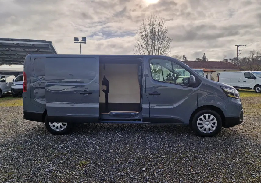 Vue de profil droit du Nissan Primastar gris urbain 2025 avec porte latérale coulissante ouverte montrant l'espace de chargement.