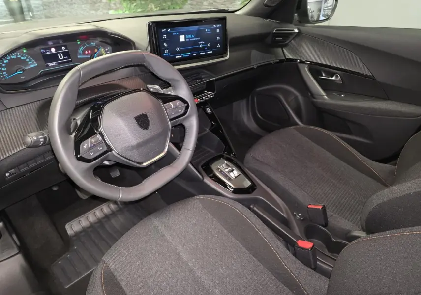 Intérieur avant droit du Peugeot 2008 gris 2025, volant compact cuir, tableau de bord numérique et écran tactile central.