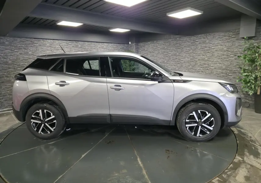 Peugeot 2008 gris métallisé vue de profil côté gauche, avec jantes noires et badge Style sur l'aile avant.
