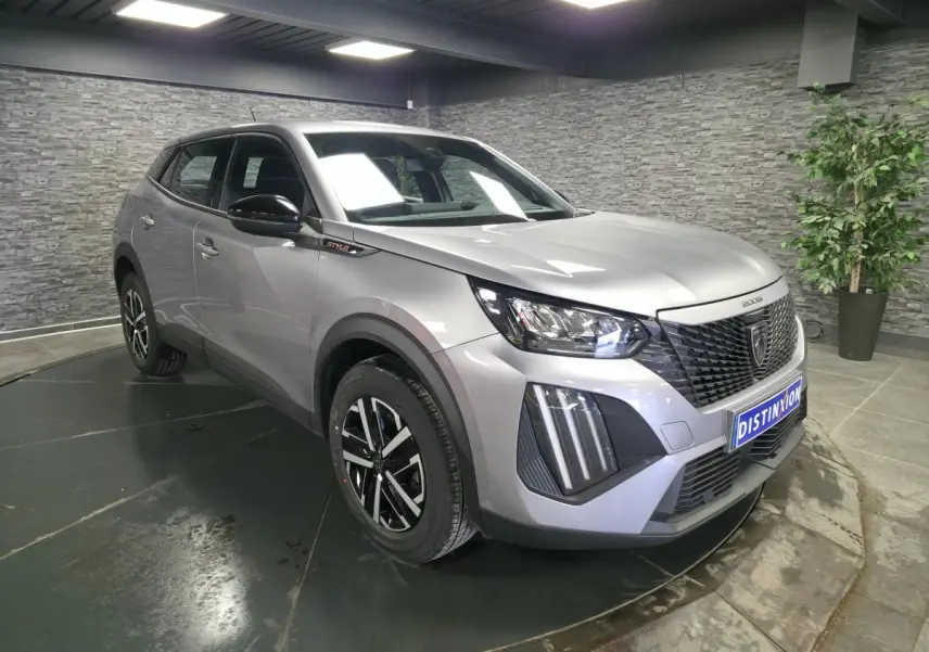 Peugeot 2008 gris métallisé vue 3/4 avant droit avec calandre noire et jantes noires et argentées.