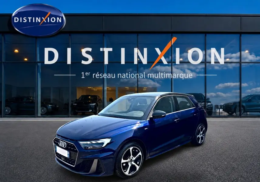 Audi A1 Sportback bleu foncé avec toit noir, vue 3/4 avant droit devant une vitrine Distinxion.