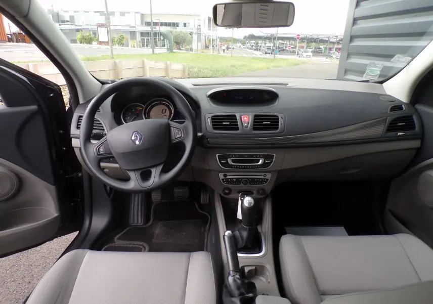 Intérieur de Renault Mégane III Expression DCI 85, vue frontale du tableau de bord et volant, sièges gris clair visibles.