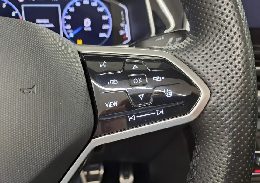 Gros plan sur les commandes du volant en cuir perforé du Volkswagen T-Roc Cabriolet gris ivoire, version R-Line 2022.