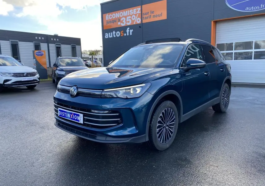 Volkswagen Tiguan 1.5 eHybrid bleu nuit en 3/4 avant droit, avec jantes alliage et calandre moderne sur parking.