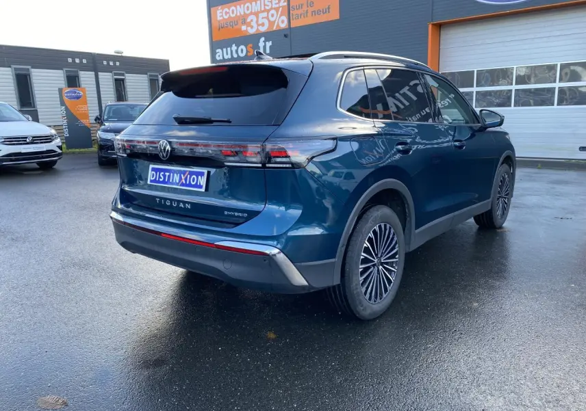 Vue 3/4 arrière droite du Volkswagen Tiguan hybride rechargeable bleu Nightshade avec feux LED et jantes stylisées.