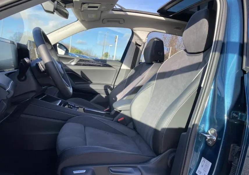 Intérieur du Volkswagen Tiguan 2025 en Nightshade Blue, vue côté gauche sur les sièges avant en microfleece et toit ouvrant panoramique.