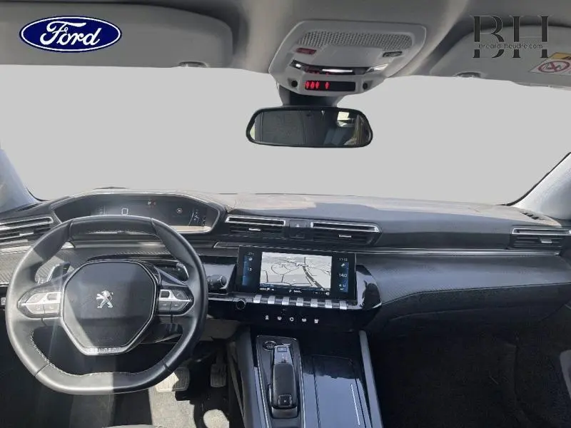 Vue intérieure avant du tableau de bord et volant cuir noir d'une Peugeot 508 SW gris Artense avec écran tactile central et inserts carbone.