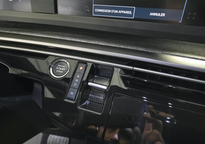 Gros plan sur la console centrale noire laquée du Peugeot 3008 gris, avec bouton start/stop et commandes de boîte auto.