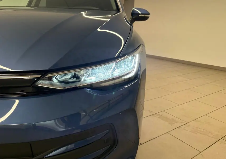 Gros plan sur l'avant droit d'une Volkswagen Golf 1.5 eTSI 2025 en Bleu Anémone avec phares LED allumés.