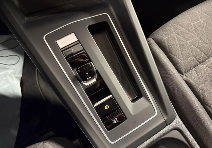 Gros plan sur la console centrale de la Volkswagen Golf 1.5 eTSI 116 DSG7, montrant la commande de boîte auto et frein électronique.