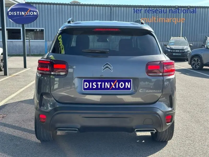 Vue arrière d’un Citroën C5 Aircross gris Platinium 2025 avec feux arrière allumés et logo distinctif sur le hayon.