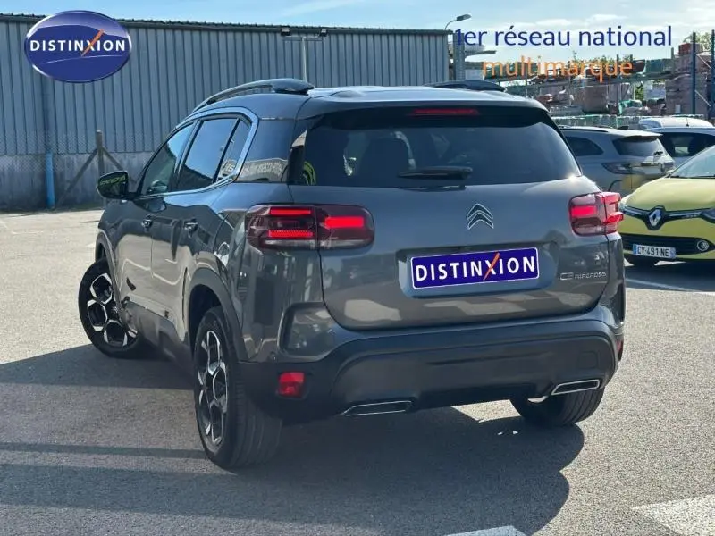 Vue 3/4 arrière droite d'un Citroën C5 Aircross gris Platinium 2025 avec feux arrière LED et jantes distinctives.
